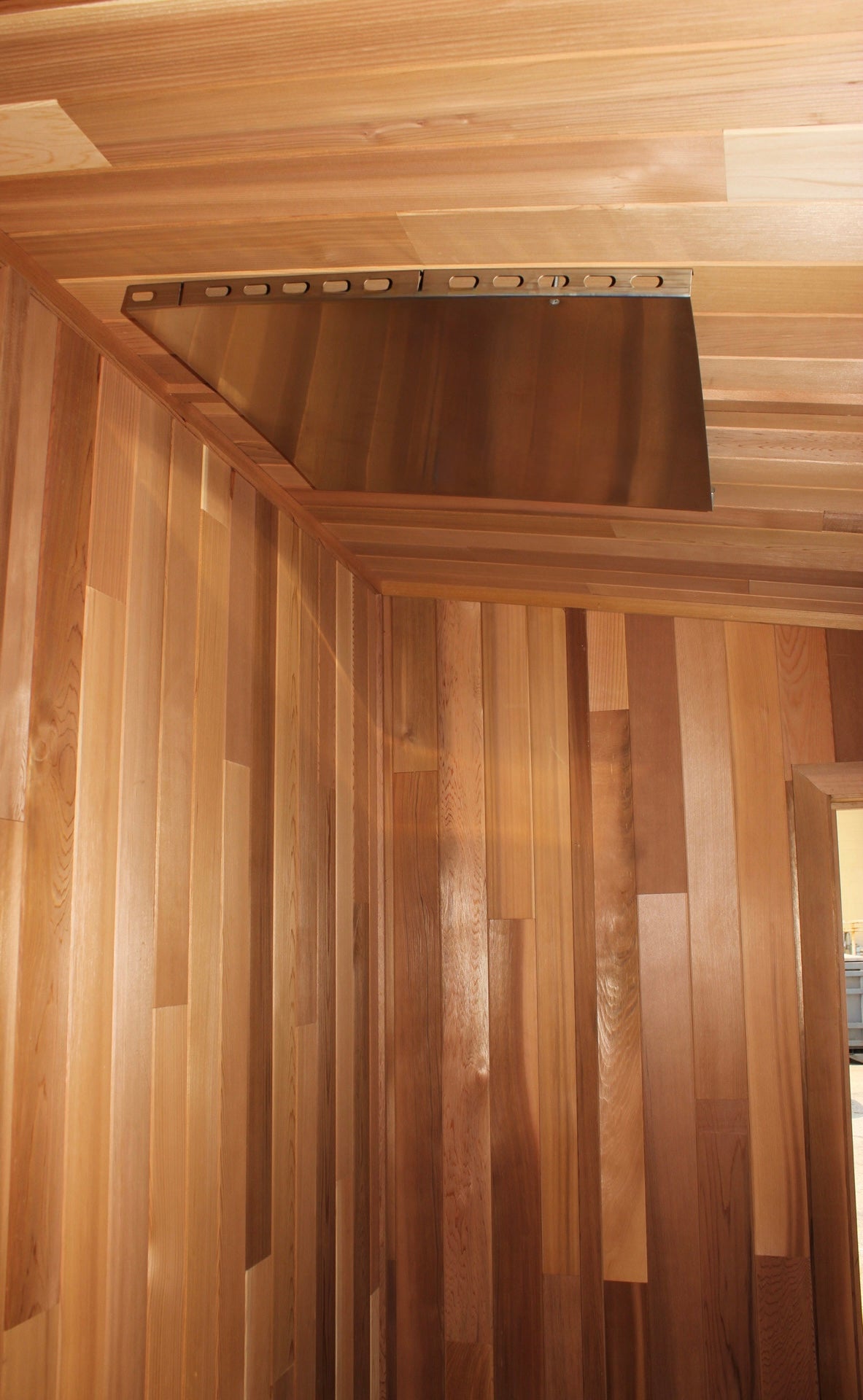 Stainless ceiling heat shield above a cedar sauna door