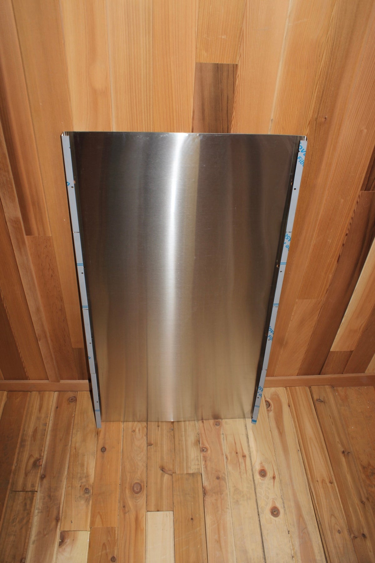Stainless heat shield mounted on a cedar sauna ceiling