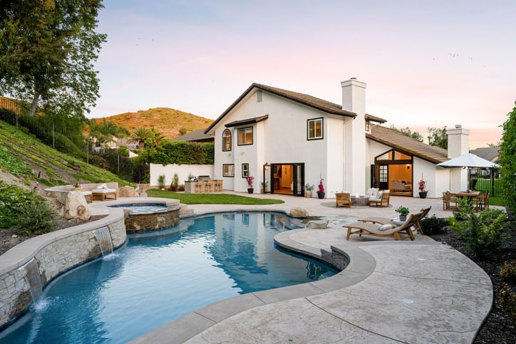 backyard renovation ideas - swimming pool, hot tub, and patio furniture at a modern house during sunset